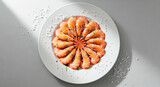 Cooked shrimps arranged in a circular pattern on a white plate, seasoned with coarse sea salt on a grey surface with natural light creating a clean and appetizing image.