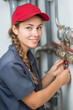© Lara - Young woman smiling while repairing plumbing at work indoors. Woman plumber tightening pipe connections