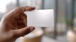 © imagemir - A close-up of a person holding a blank card, showcasing a sleek, modern design in a bright, contemporary setting.