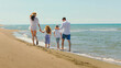 © Videophilia - Family walking together on a sandy beach at the sea, holding hands and enjoying warm sunny weather during their summer vacation, splashing feet in the ocean waves