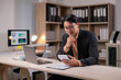 © Wasana - A man in a suit is sitting at a desk with a laptop and tablet in front of him