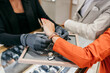 © Dusko - Sales associate in protective gloves assisting a customer with trying on an elegant wrist watch in a luxury jewelry store, offering specialized retail service