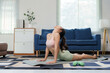 © amnaj - Woman stretching in cobra pose during a home workout on a yoga mat, focusing on wellness and healthy lifestyle