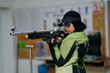 © Minet - Female athlete wearing professional shooting uniform and hijab carefully aiming with an air rifle at an indoor range.
