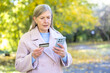 © Liubomir - Senior woman feeling confused holding credit card and phone