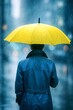 © Noor - A figure in a blue raincoat stands beneath a bright yellow umbrella as heavy rain falls in an urban setting, conveying resilience and the moody atmosphere of a rainy city.