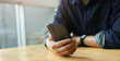 © chinnarach - close up businessman hand hold smartphone to surfing the internet and check work or mail on website while sit in the living room in weekend for business technology and lifestyle concept