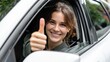 © Newleks - Young woman driver smiling and giving a thumbs up gesture, expressing approval, happiness, success, and positivity while looking out of her car window
