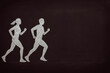 © mailcaroline - A chalk drawing of a man and woman running together on a black background. Physical fitness, sports, recreation, partnership design element with copy space.