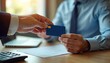© Vadym - Man in blue shirt receives credit card from bank worker. Businessman gets card for financial transaction. Hand of bank teller gives card to client across wooden desk with calculator and papers.