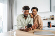 © Miljan Živković - Young black couple sharing smart phone in kitchen at home