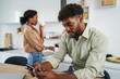 © Miljan Živković - African american man using smart phone in kitchen