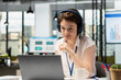 © DC Studio - Caucasian corporate worker wearing headphones uses laptop to read emails and prepare project presentation. Female employee listening to music and working on digital device in modern workspace.