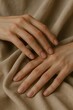 © saeedy - Close-up of elegant hands resting on soft beige fabric, showing natural beauty, calmness, and gentle touch.