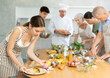 © JackF - Positive young woman attendee of cooking course decorating meal made of salmon fish together with others