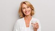 © Johannes - happy middle aged 50s woman holding pill and glass of water taking dietary supplements portrait of smiling adult attractive woman taking care of health in menopause isolated on white no logos no bran