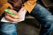 © Jorge Elizaquibel - Journalist writing notes outdoors in a notebook with a green pen
