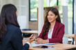 © Crystal - Two professional businesswomen having a conversation during a job interview or mentoring session at a modern office desk