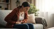 © Yasmeen  - Young woman experiencing abdominal pain holding stomach in discomfort sitting on sofa at home
