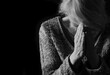 © herlanzer - woman praying with hands together on grey black background with people stock image stock photo