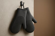 © Aleksandra - Pair of modern silicone oven mitts hanging on kitchen wall hook, textured grip for heat protection and safety in cooking