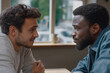© stefanholm - Two diverse men engage in a deep, supportive conversation at a cafe, highlighting authentic male vulnerability and connection.