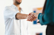 © Studio Marmellata - A man and a woman shake hands, signifying a successful business deal or a friendly greeting in a modern office setting.