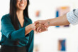 © Studio Marmellata - Two business professionals shake hands, signifying a successful agreement or partnership. The woman on the left smiles warmly, conveying a positive outcome.