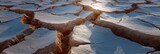 Sunlit cracked earth with deep fissures in arid landscape