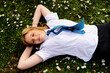 © Austockphoto - Teenage girl with a blue tie lying on grass field with tiny white flowers