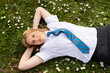 © Austockphoto - Teenage girl with a blue tie lying on grass field with tiny white flowers
