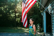 © Cavan Images - Teen girl standing by an American flad in front of a garage