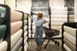 © Ivan Traimak - Woman shopping for wallpaper in a home decor store during the daytime with various patterns surrounding her