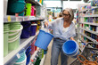© Ivan Traimak - Choosing colorful buckets in a store's home goods aisle during a busy afternoon