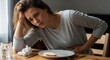 © siripimon2525 - Woman Sitting at Table with Stomach Pain and Leftover Food