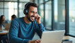 © Pete - Happy man wearing headphones uses laptop in bright office. He laughs while working at his computer. Colleagues work in background. Modern workspace.