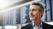 © vadosloginov - Man in a suit looking thoughtfully at flight information display in a busy airport terminal during the day