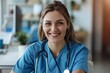 © Baba Images - Smiling young woman doctor in blue scrubs