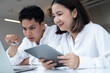 © Bordinthorn - Man and woman discussing work with laptop and tablet in modern office, representing teamwork, startup collaboration, digital project, online communication, and professional business productivity.