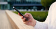 © serg - Close up of males hands use mobile phone outdoors