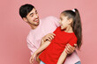 © ViDi Studio - Young smiling happy parent man with child girl she wear red casual clothes. Daddy little kid daughter hugging cuddle play together isolated on plain pink background. Father's Day Love family concept.