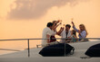 © Jacob Lund - Wealthy family toasting to health and happiness on a luxury boat at sunset
