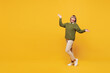 © ViDi Studio - Full body side view happy winner smiling elderly blonde woman she wears green sweater casual clothes spread hands dance isolated on plain yellow orange background studio portrait. Lifestyle concept.