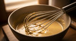 © ANT - Close up of a bowl with whisk and liquid mixture.