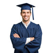 © Selim - A cheerful young man wearing a graduation cap and gown with his arms crossed smiling confidently isolated on transparent background