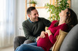 © NDABCREATIVITY - Beautiful young couple with pregnant wife at home with her husband touching his wife's belly