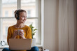 © Halfpoint - Young female student with headphones sitting at the table and studying.