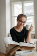 © Halfpoint - Young female student having cup of coffee while studying.