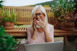 © Halfpoint - Older woman having cup of tee while working from homeoffice, sitting on terrace.