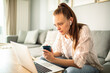 © Davor - Young woman using laptop at home